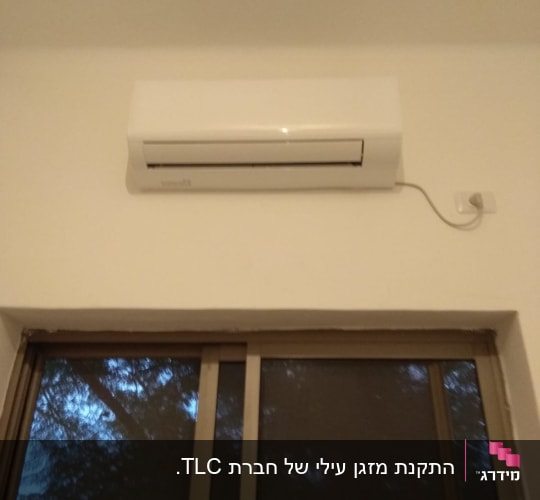 מזגן קיר לבן מותקן מעל חלון